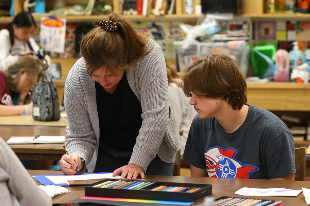 Mrs. Goans helps a student with shading his artwork in AP Studio Art